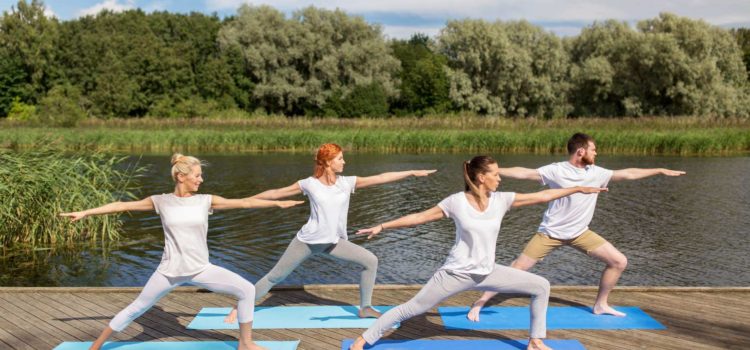 Fyra personer utövar yoga på en brygga